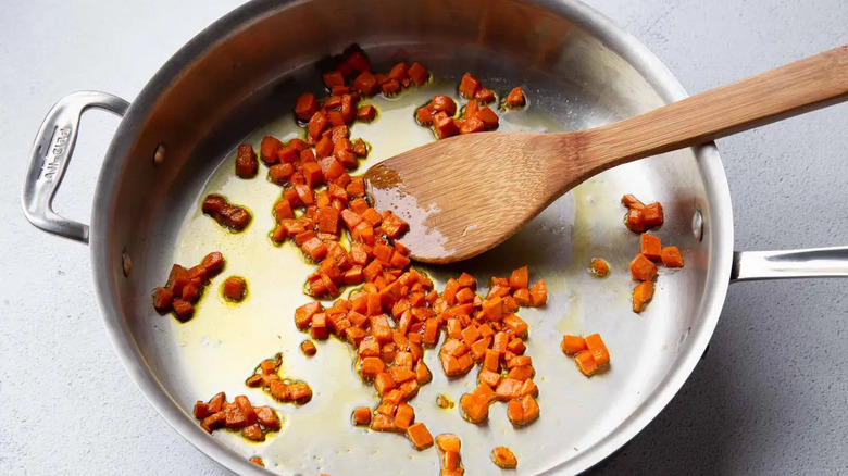 Finely chopped carrots in skillet with wooden spatula