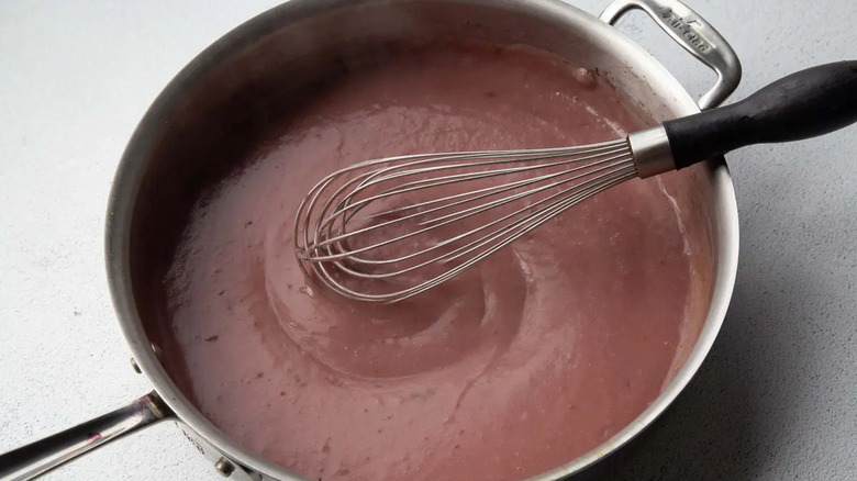 Thick red mixture in skillet with whisk