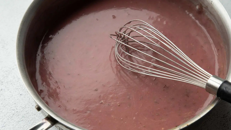 Thick reddish mixture in skillet with whisk