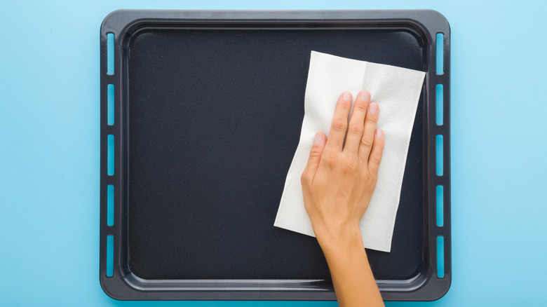 A person wiping a clean baking sheet