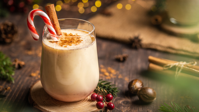 Glass of eggnog with candy cane and cinnamon stick