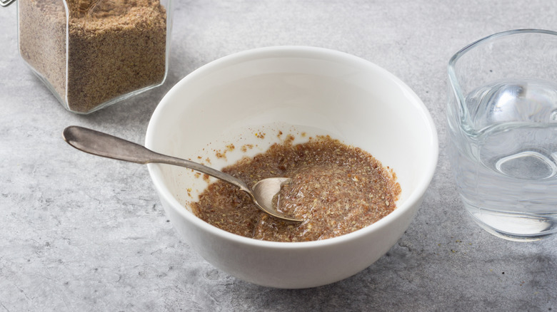 Bowl of flax egg by water and ground flaxseed