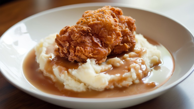 fried chicken with mashed potatoes and gravy in a white bowl