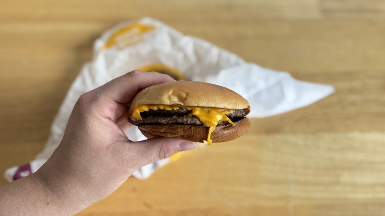 Hand holding a double cheeseburger