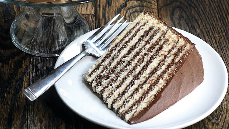 closeup of sliced smith island cake on white plate and wooden table