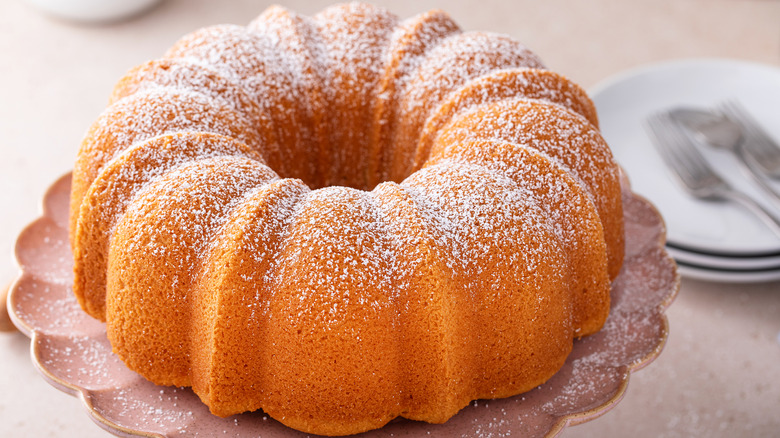 white bundt cake dusted with powdered sugar on cake stand