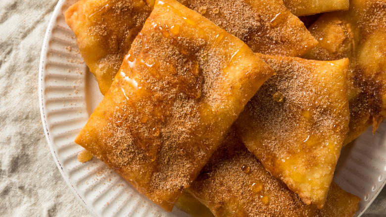 plate of Mexican sopapillas with cinnamon sugar and honey drizzle on white plate