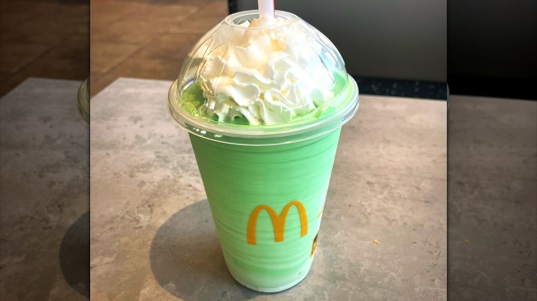 A McDonald's Shamrock Shake with whipped cream and a dome lid