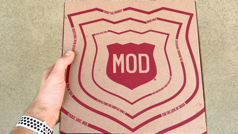 Hand holding MOD Pizza box