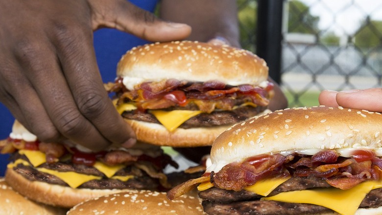 Hands grabbing Bacon King burgers from Burger King