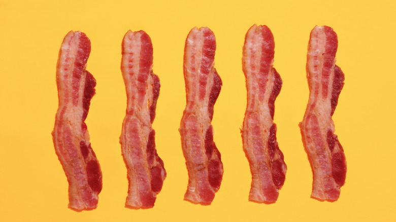 Five strips of bacon on a yellow background