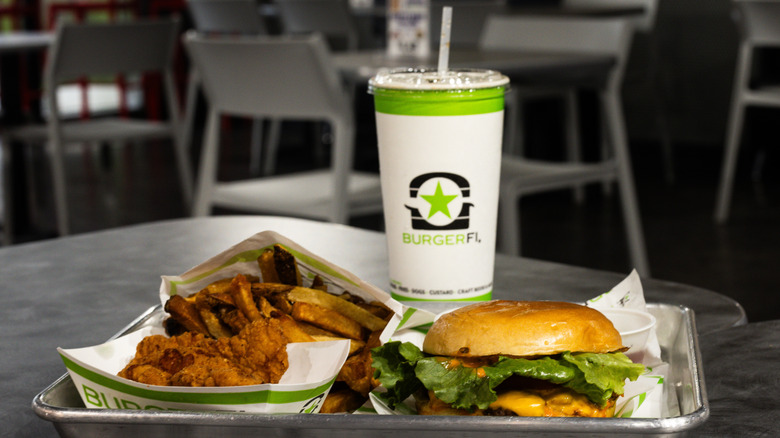 Chicken tenders, fries, a burger, and a drink from BurgerFi on a tray