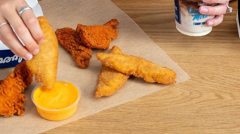 Chicken tenders being dipped into sauce