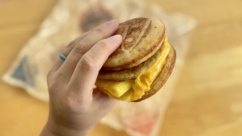 Hand holding a McDonald's Sausage, Egg & Cheese McGriddle