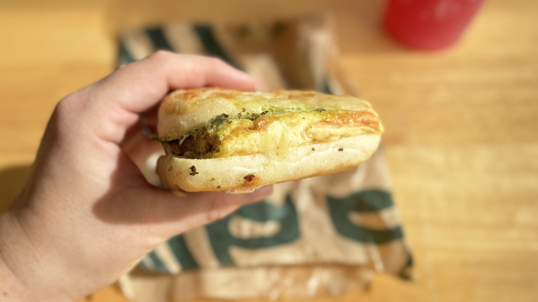 Hand holding Starbucks' Egg, Pesto & Mozzarella Sandwich