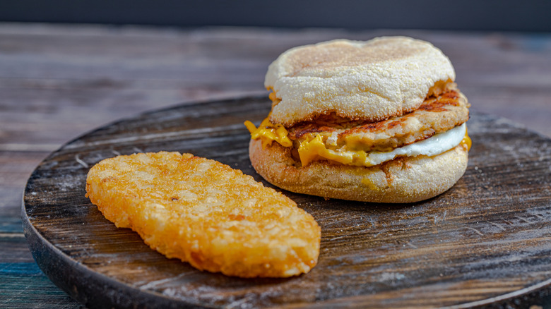 McDonald's Egg McMuffin and hash browns on a wooden plate