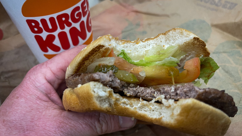 Whopper with bites taken out of it by Burger King cup