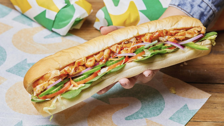 Hand holding Subway chicken sandwich