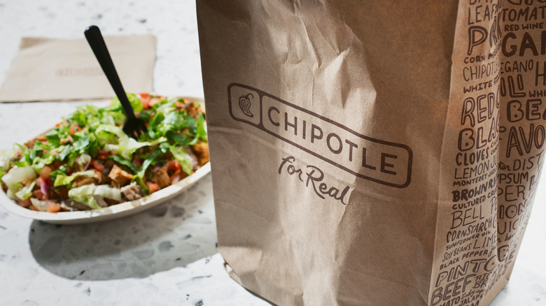 Chipotle bag with burrito bowl in background