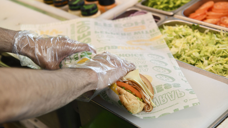 Employee wrapping Subway sandwich