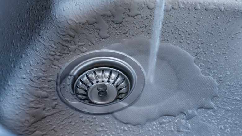 Closeup of running tap water into a kitchen sink drain