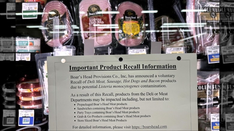 A piece of paper detailing Boar's Head recall information is taped to a deli meat refrigerator door.