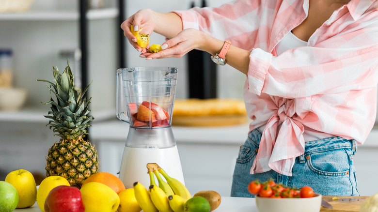 Woman adding fruit to blender