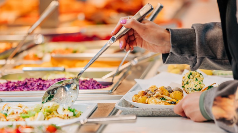 Hand holding a serving utensil in buffet stand