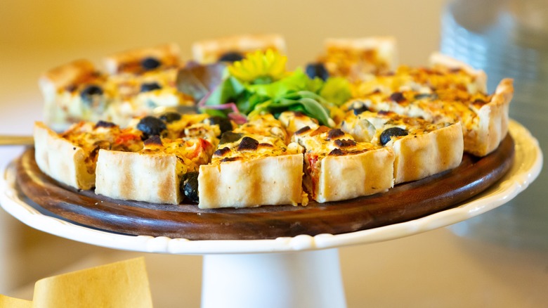 Sliced quiche on cake stand at buffet