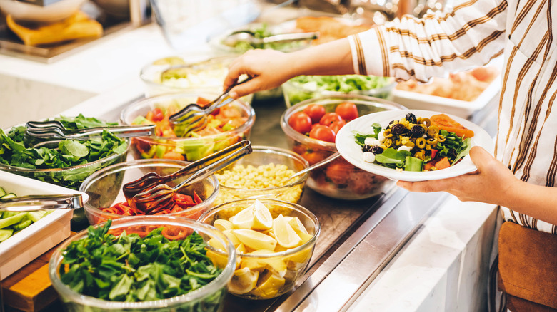 Person serves up food from buffet salad bar