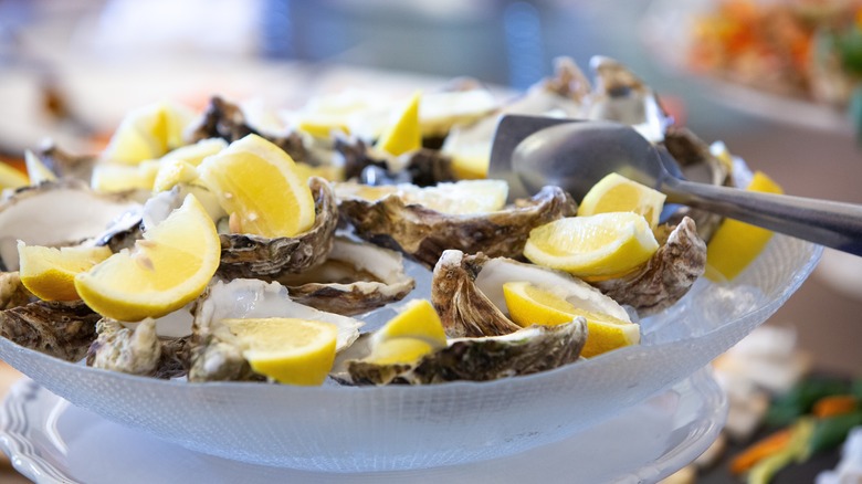 Raw oysters on half-shell with lemon wedges over ice