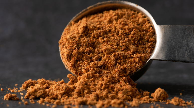 Close up of a tablespoon of taco seasoning spilling on a surface