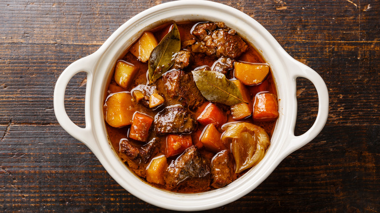 A pot of of beef stew laying on table.