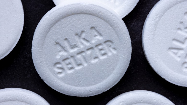 A close up of Alka-Seltzer tabs on a black background