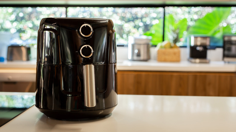 A black air fryer on top of a white counter top