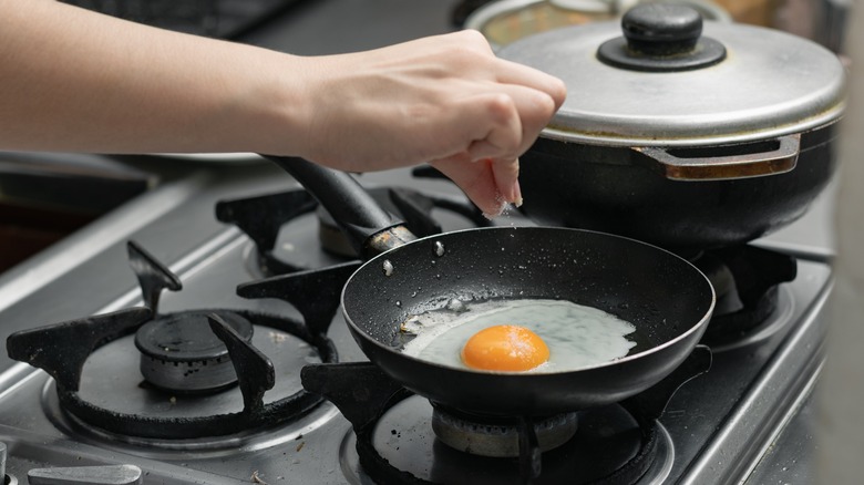 Salting fried egg in a pan