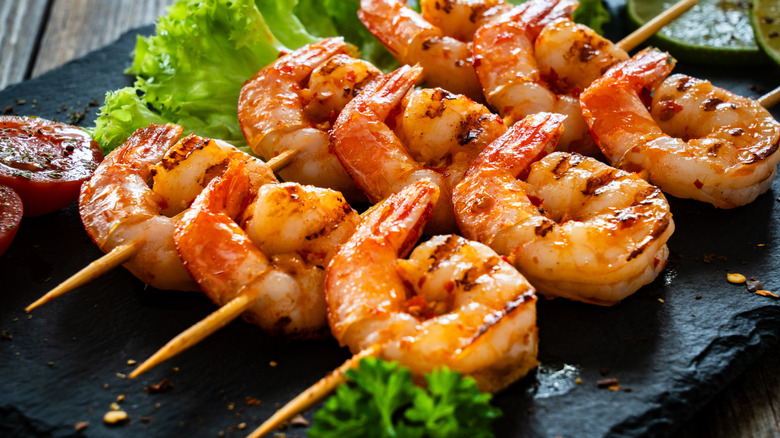 Skewers of grilled shrimp on a black plate