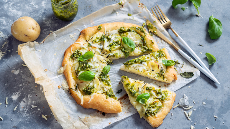 homemade pesto pizza with cheese, basil, and pine nuts