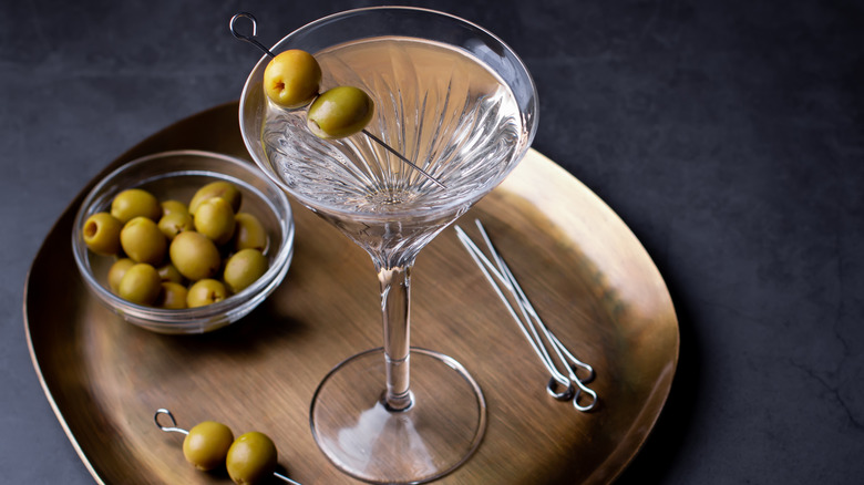 dirty martini on a tray with a bowl of olives for garnish