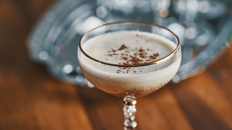 Light-colored drink in coupe glass with cinnamon sprinkle