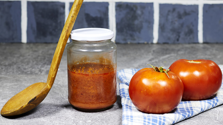 pasta sauce in jar with wooden spoon and fresh tomatoes