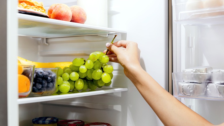 Person reaching for grapes in fridge