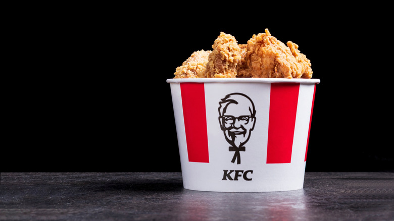 A KFC bucket standing on a black surface.