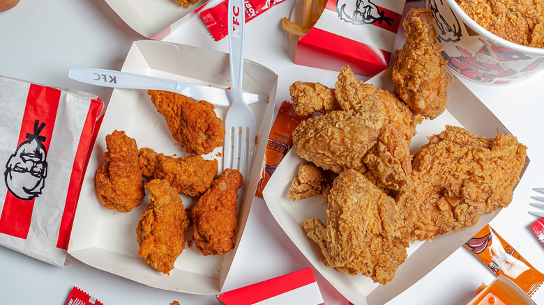 An array of KFC food items, including fried chicken, chicken wings, and fries on a table.