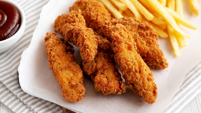 Close-up of chicken tenders on a plate with fries