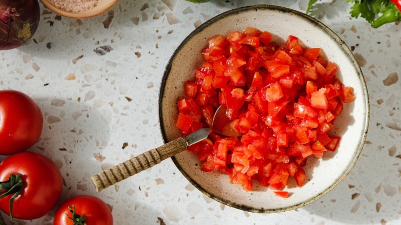 Bowl of diced tomatoes with spoon inside