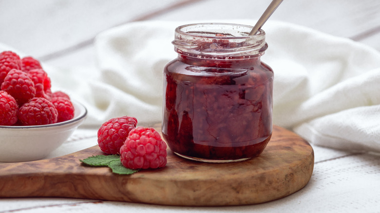 A jar of raspberry jam with fresh raspberries