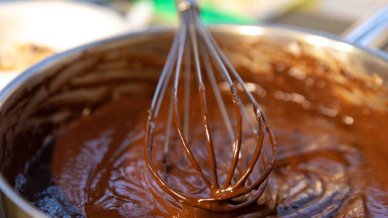 A bowl of brownie batter with a whisk in the center