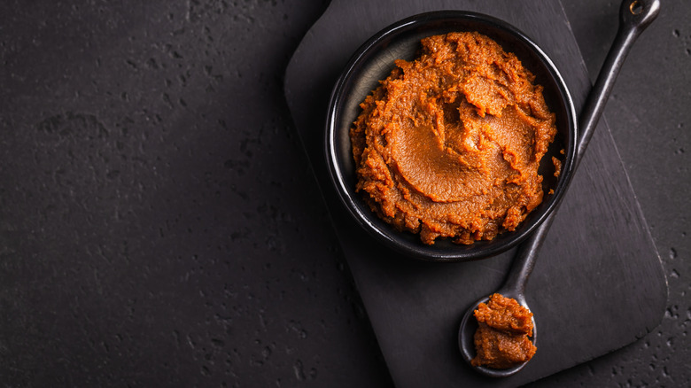 Small bowl of miso paste next to a scooping spoon