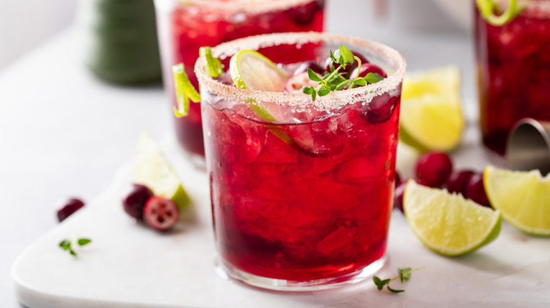 A red margarita with a lime slice and thyme sprig garnish